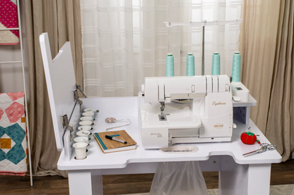 Close-up of a Baby Lock serger sewing machine on a white workstation with sewing accessories