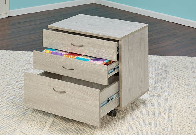 Wooden sewing storage cabinet with open drawers revealing fabric inside