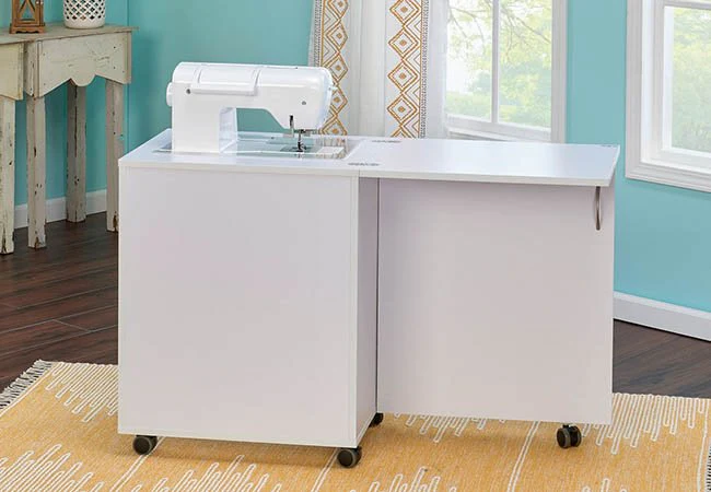 White sewing cabinet with an extended work surface and built-in sewing machine