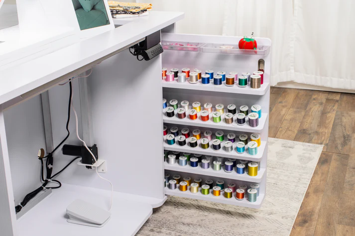 Sewing cabinet with a pull-out thread storage rack filled with colorful spools