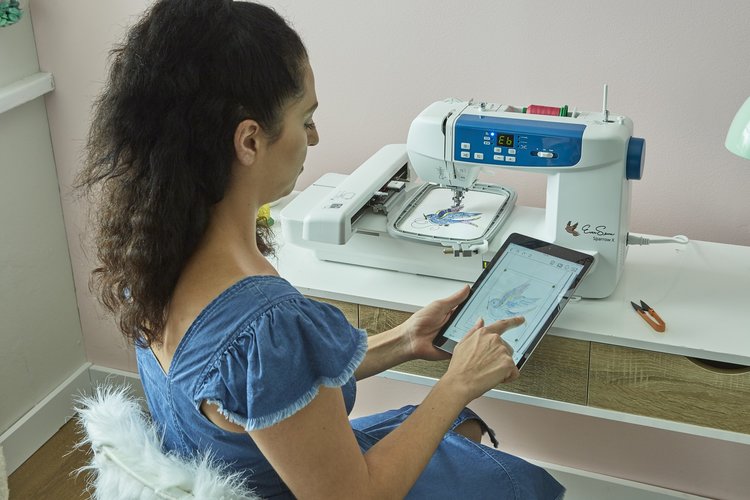 Woman operating an embroidery machine using a tablet